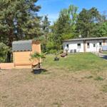 Haus mit Garten, Sauna und Bäumen im Hintergrund.