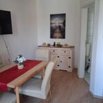 Dining area with table, chairs, and TV. Wall artwork. View into bathroom.