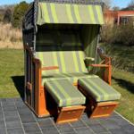 High-quality beach chair with green-white striped fabric and wooden frame on stone tiles.