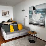 Wohnzimmer mit Sofa, Couchtisch und Wandbild. Holzboden und helle Wände.