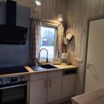 Kitchen with stove, sink, and window. Wooden walls and kitchen counter.