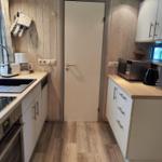 Kitchen with countertops, sink, stove, and microwave. Wooden walls and floor.