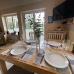 Dining table set for four, flower vase, and TV mounted on the wall.