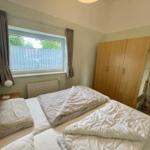 Bedroom with double bed, wardrobe, and window with curtains.