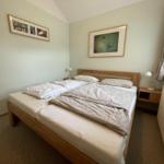 A bedroom with a double bed, two bedside tables, and wall pictures.
