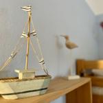 A wooden sailboat with striped flags sits on a table next to a bird figurine.