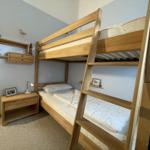 A bedroom with a wooden bunk bed and a nightstand.