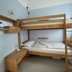 A bedroom with a wooden bunk bed and a bedside table.