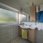 Bathroom with sink, mirror, and window with tinted glass.