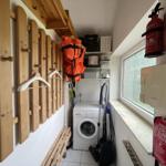 Laundry room with washing machine, coat rack, and window