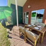 Terrace with table, chairs, grill, and green umbrella.