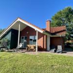 Red brick house with patio and garden. Outdoor seating and barbecue area.