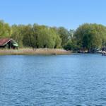 A lake with boats and a house on the shore among trees.