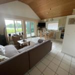 Living and dining area with kitchen, wooden ceiling, and large window. Furniture is present.