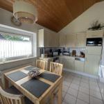 Kitchen with dining table, wooden ceiling, and window with curtains.