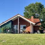 A house with a red roof and green extension. Outdoor furniture is on the lawn.