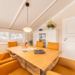 Dining room with wooden table, orange chairs, and view of snow.