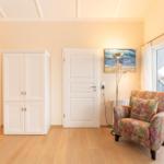 Room with white doors, wardrobe, armchair, and window to terrace.