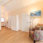 Living area with wooden floor, white doors, and a colorful armchair.