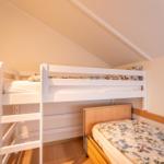 Room with bunk bed and single bed under sloped ceiling.