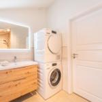 Bathroom with washing machine and dryer, mirror cabinet and towel rack.