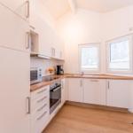 Kitchen with white cabinets, wooden countertops, and windows for outside view.