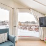 A room with a blue armchair, TV, and view of a snowy landscape.