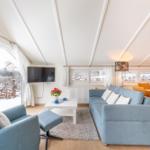 Living and dining area with sofa, armchair, TV, and view of snow.