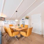 Dining room with wooden table, yellow chairs, and windows overlooking snow.
