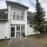 Haus mit großem Fenster und Eingangstür. Vor dem Haus steht ein großer Baum.
