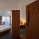 Schlafzimmer mit Bett, Kleiderschrank und Blick auf Balkon.