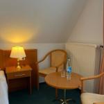 Zimmer mit Holztisch, zwei Stühlen, Nachttisch und Lampe unter schräger Decke.