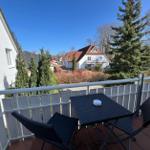 Terrasse mit Tisch und Stühlen, Blick auf Haus und Bäume.