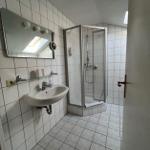 Badezimmer mit Dusche, Waschbecken und Spiegel an der Wand.