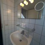 Badezimmer mit Waschbecken, Spiegel und beleuchteter Wand
