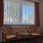 Zwei Stühle und ein Tisch stehen vor einem Fenster mit Vorhängen.