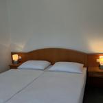 Doppelbett mit zwei Nachttischen und Lampen an der Wand