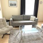 Wohnzimmer mit Sofa, Sessel, Glas-Tisch und Teppich