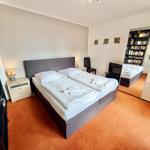 Schlafzimmer mit Doppelbett, Nachttisch, Spiegel und Bücherregal.
