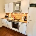 Küche mit weißen Schränken, Holz-Arbeitsplatte und Edelstahlgeräten.
