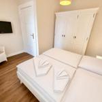 Schlafzimmer mit Doppelbett, Kleiderschrank, TV und Stuhl.