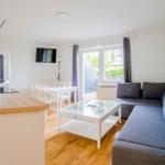 Wohnung mit Kücheninsel, Essbereich und Wohnzimmer mit Sofa und Glas-Tisch.