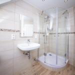 Badezimmer mit Dusche, Waschbecken und Spiegel an der Wand.