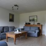 Wohnzimmer mit zwei grauen Sofas, Holztisch und Fernseher an der Wand.
