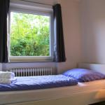Ein Bett mit lila Bettwäsche und einem Fenster mit Blick auf Bäume.