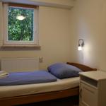 Ein Schlafzimmer mit Bett, Nachttisch und Fenster zum Garten.