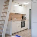Küche mit weißen Schränken, Herd und Treppe zur oberen Etage.