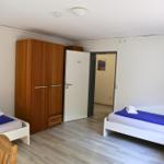 Zimmer mit zwei Betten, Schrank und Fernseher an der Wand.