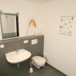 Badezimmer mit Waschbecken, Toilette und Spiegel an der Wand.