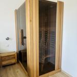 Dampfsauna mit Holzrahmen und Glaswand. Nebenbei steht ein kleiner Holzschrank.